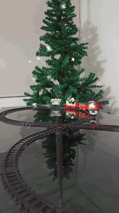 Tren navideño funcionando alrededor del árbol con luces y vapor